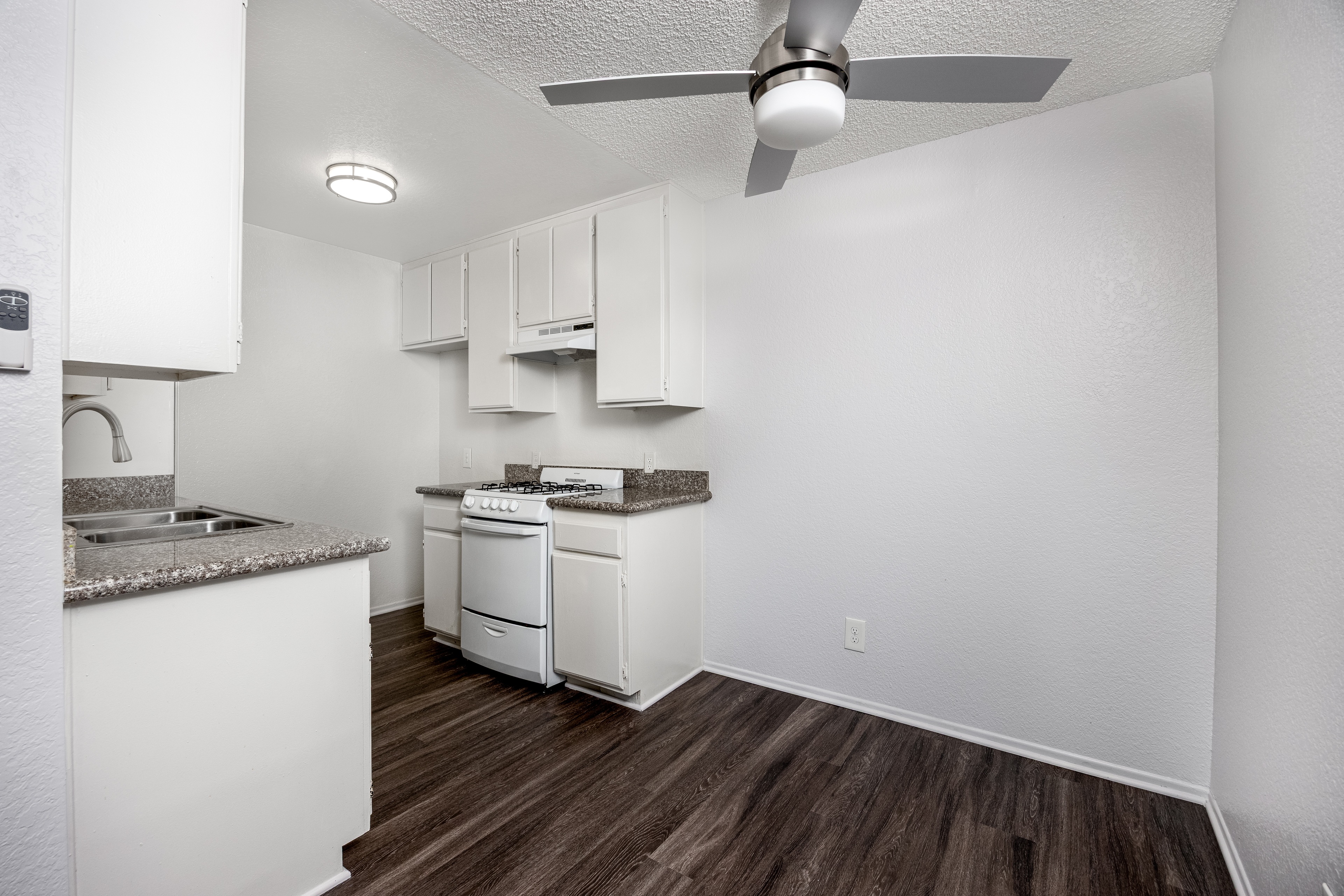 A kitchen with white cabinets and a wood floor.
